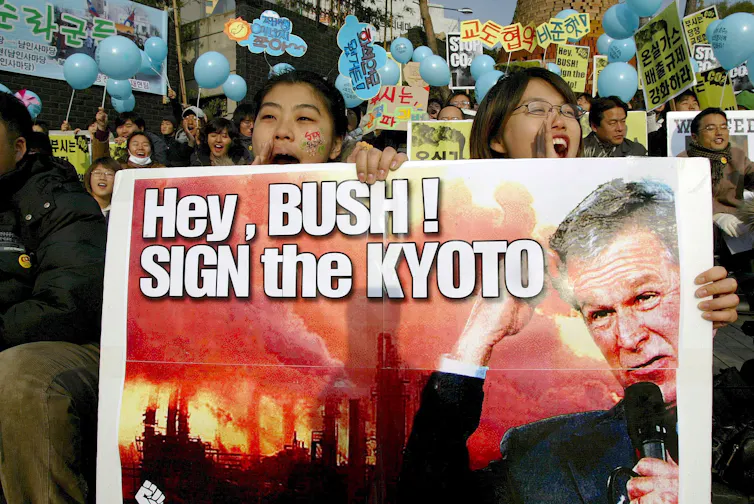 Protesters with 'hey bush, sign the kyoto' sign