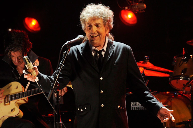 Bob Dylan performing in LA in 2015 wearing a black suit.