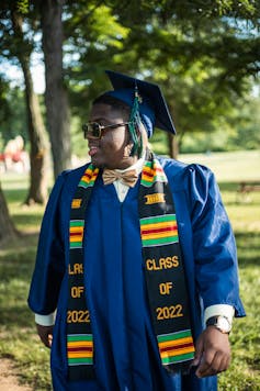 A person standing in graduation robes.
