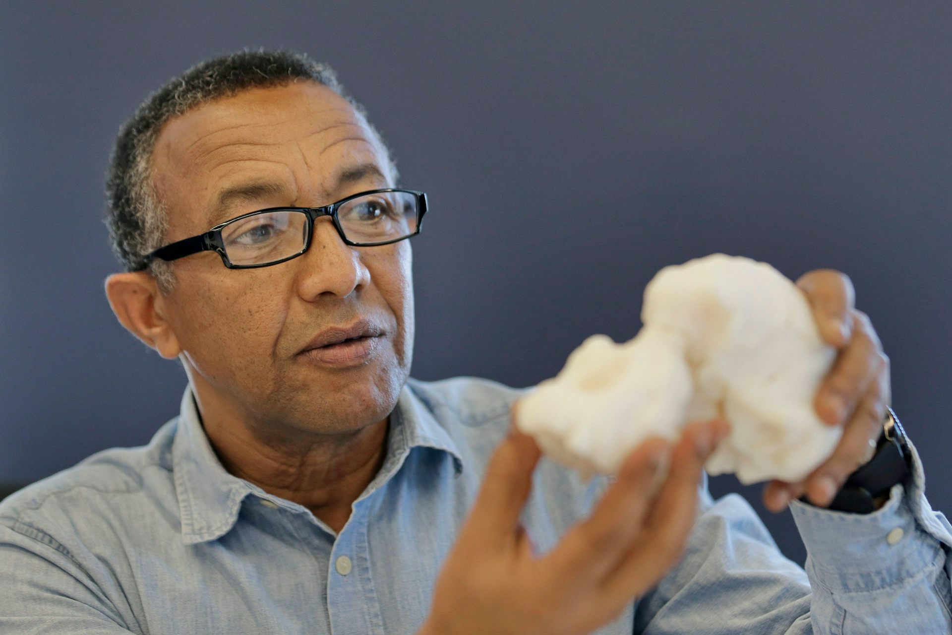 Close-up of a man holdiing a replica of an ancient hominin skull.