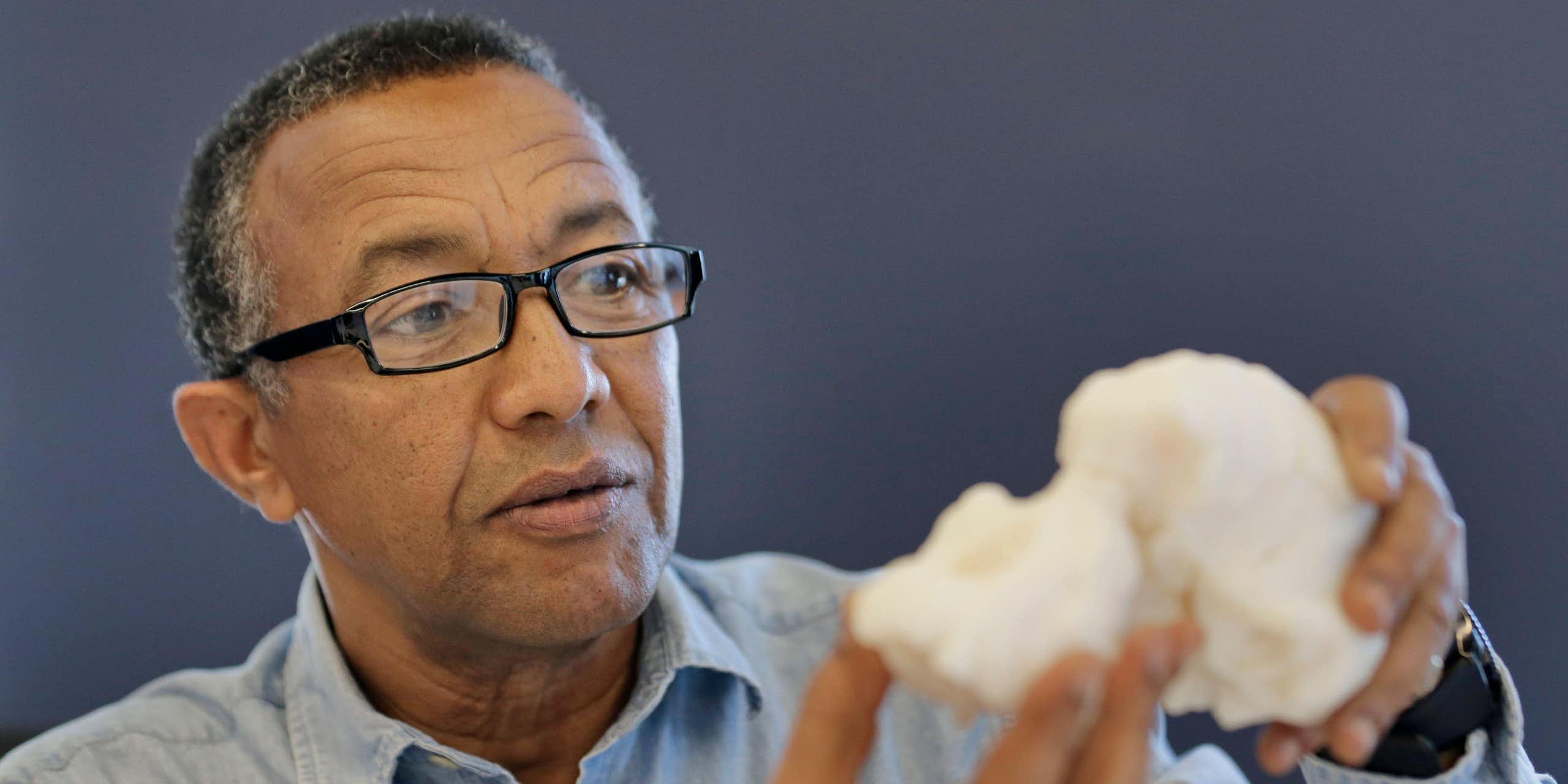 Close-up of a man holdiing a replica of an ancient hominin skull.