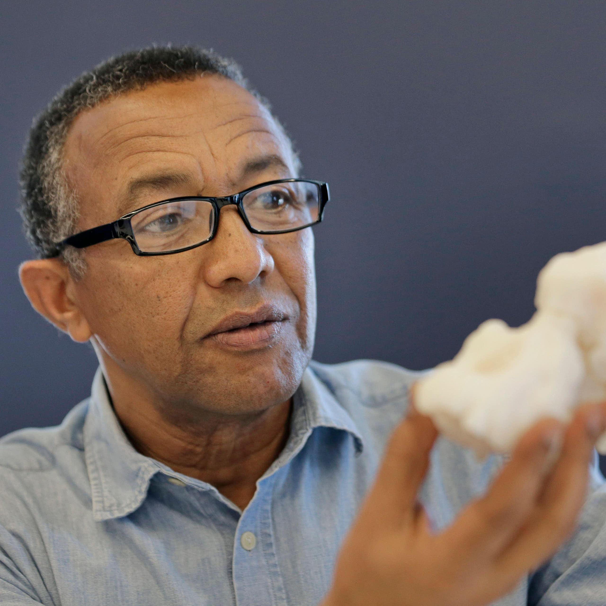 Close-up of a man holdiing a replica of an ancient hominin skull.