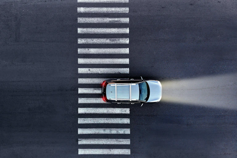 Top down view of a car driving across a zebra crossing.