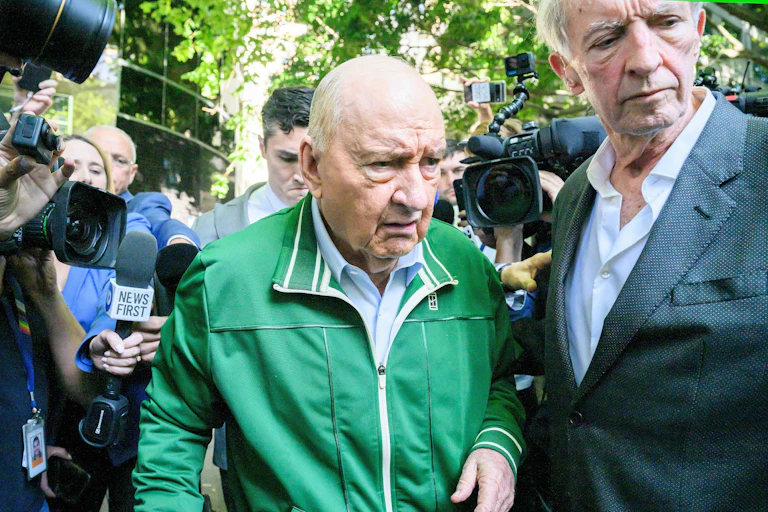 Alan Jones wearing a green tracksuit top and surrounded by media