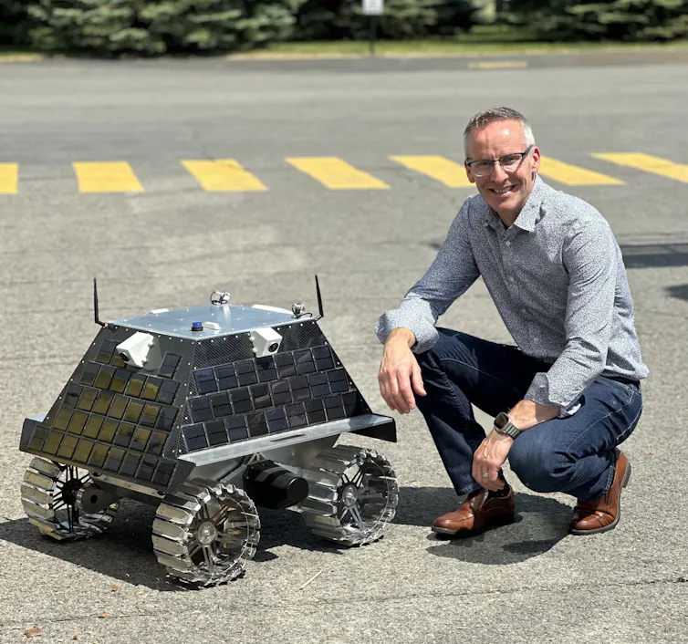 A man crouches next to a small space vehicle.