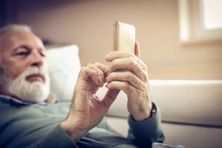 A man looks at his phone while in bed.