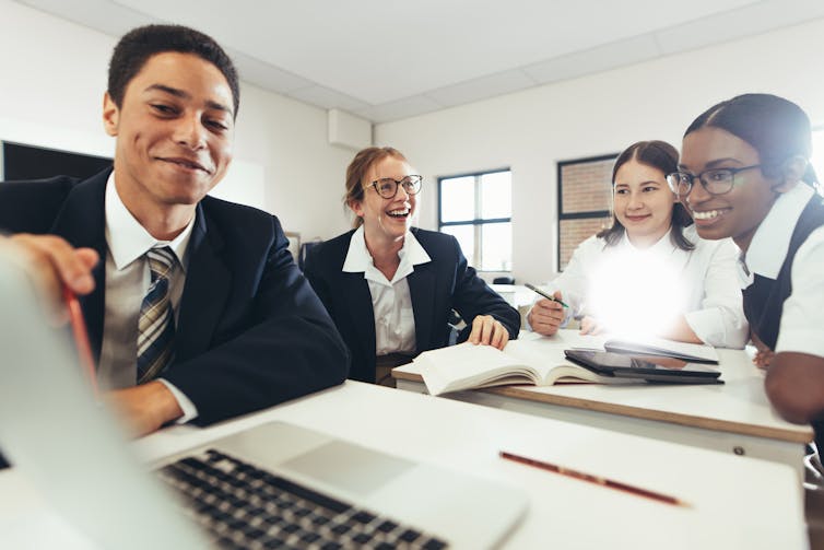 A group of students work together around a laptop.