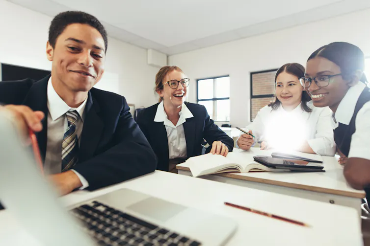 A group of students work together around a laptop.