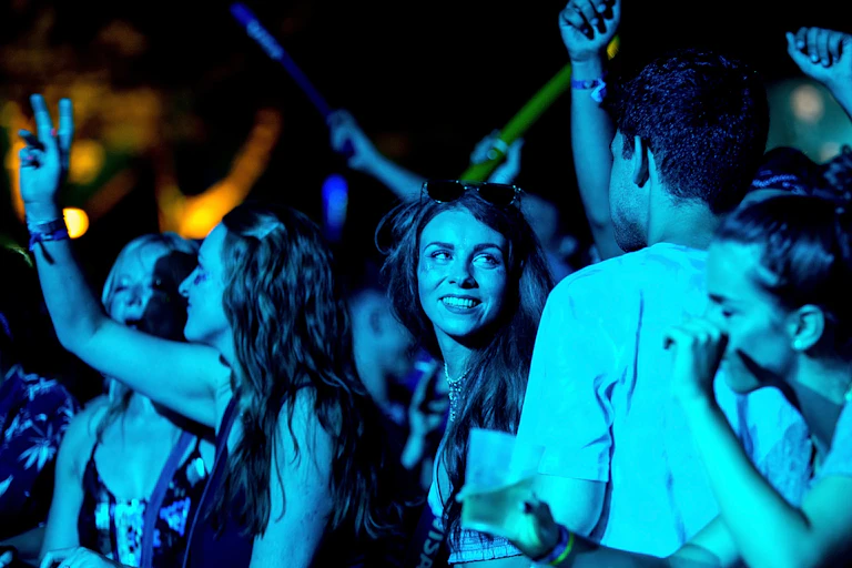 A woman in a dancing crowd looks at a man.