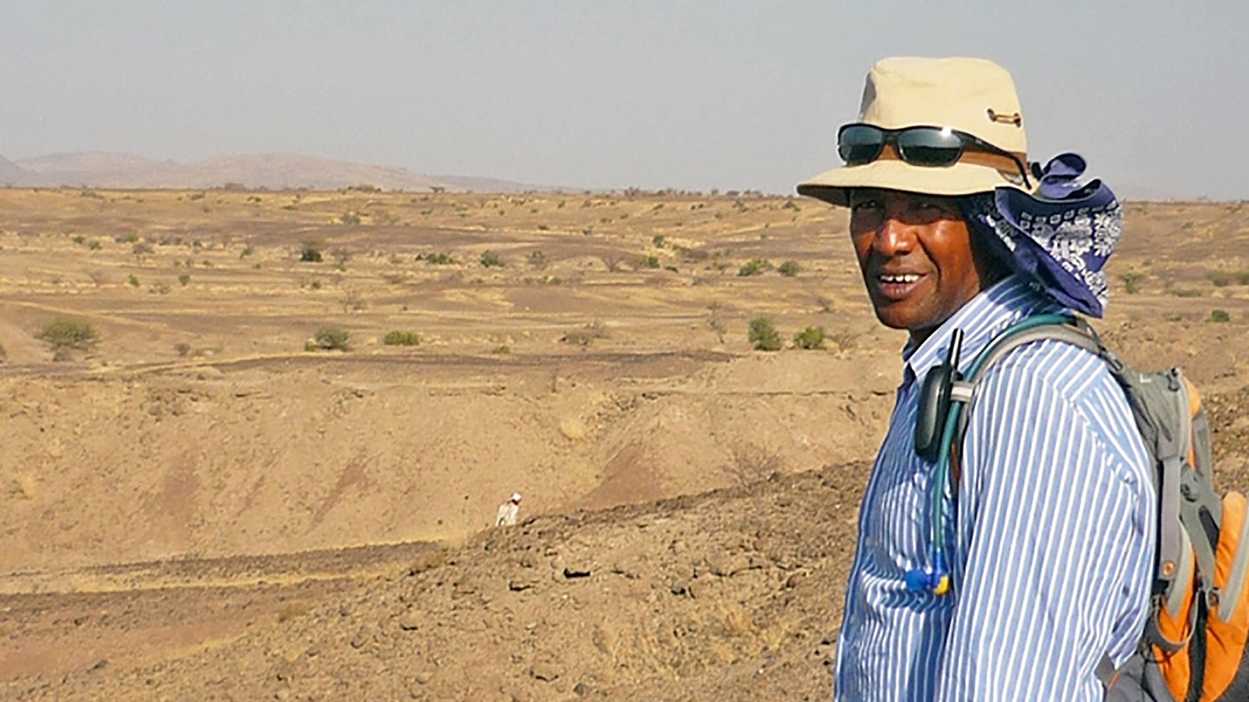 Scientist wearing a hat with desert landscape behind him