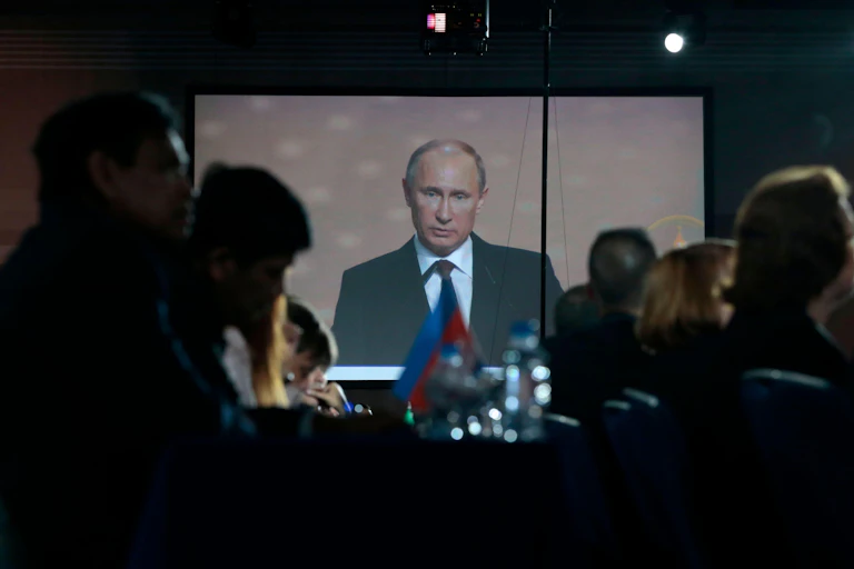 Putin on a screen addressing a crowd.