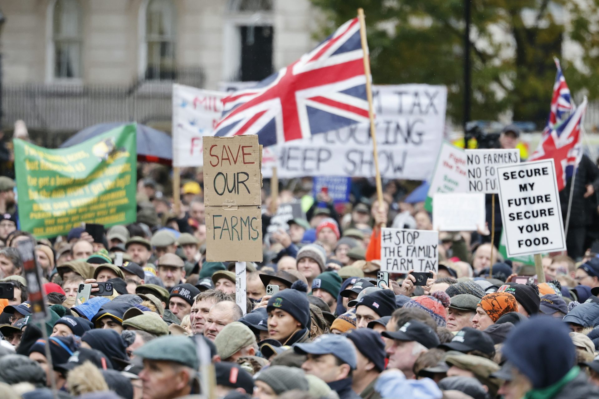 A crowd waving flags and holding placards, one reading 'save our farms'.