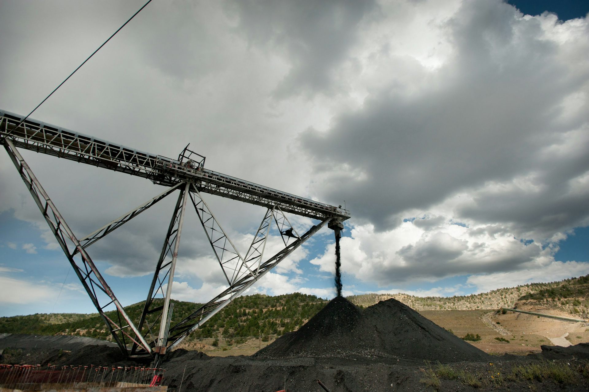 Coal falls from a conveyor belt into a large mound.