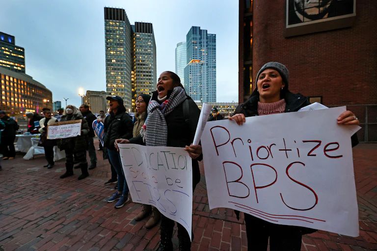 People hold signs reading 'Prioritize BPS' and 'Education should be first'