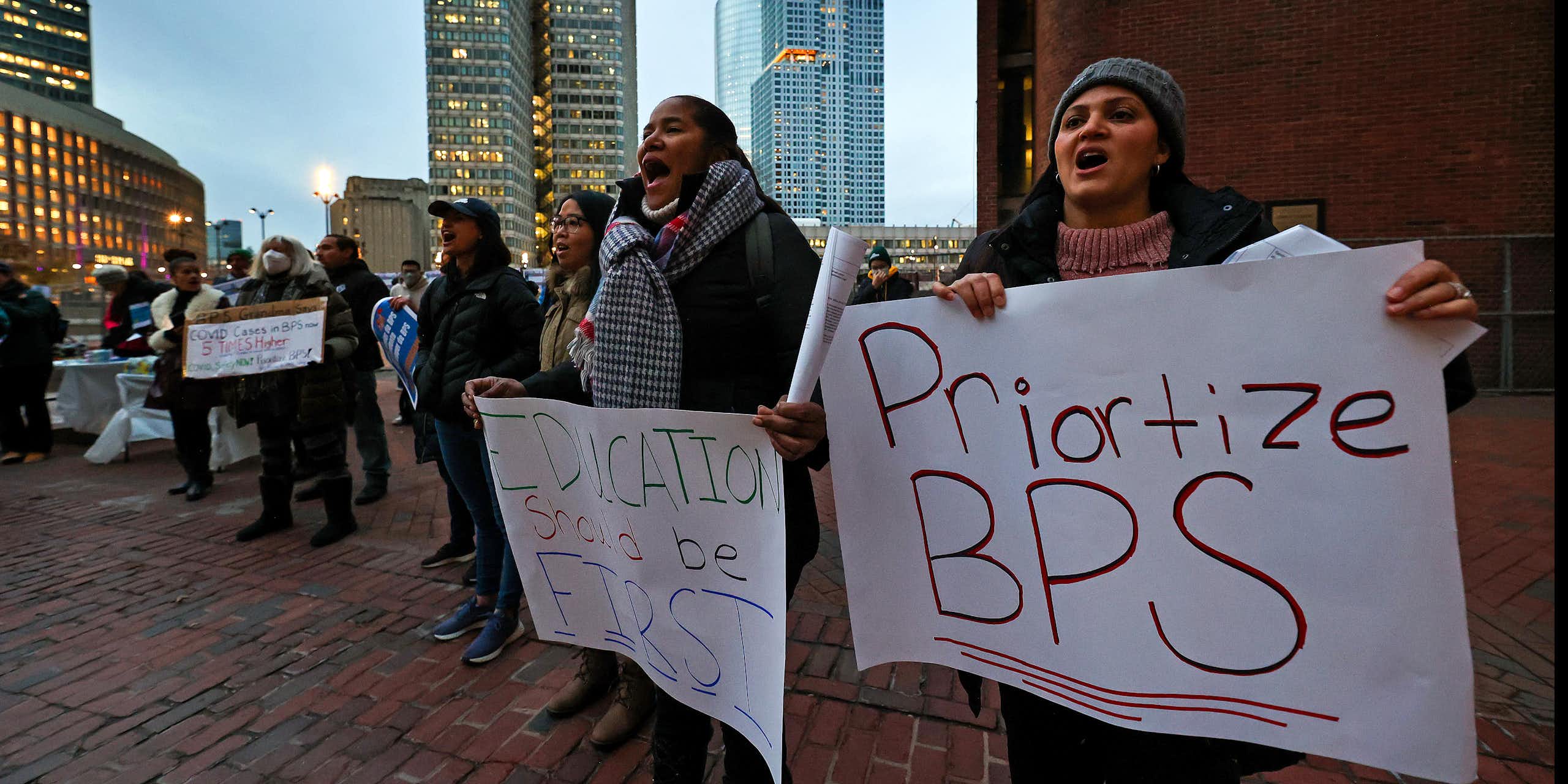 People hold signs reading 'Prioritize BPS' and 'Education should be first'