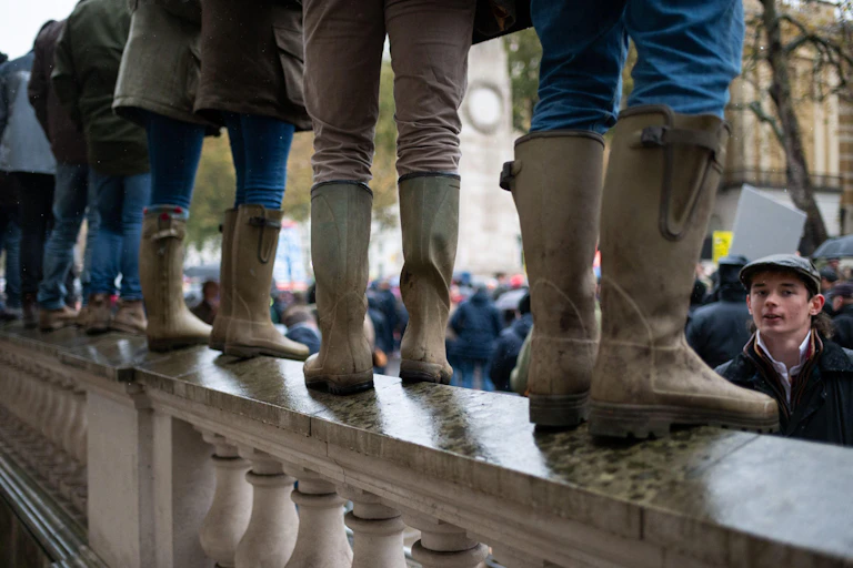 A line of people in wellies standing on a wall.