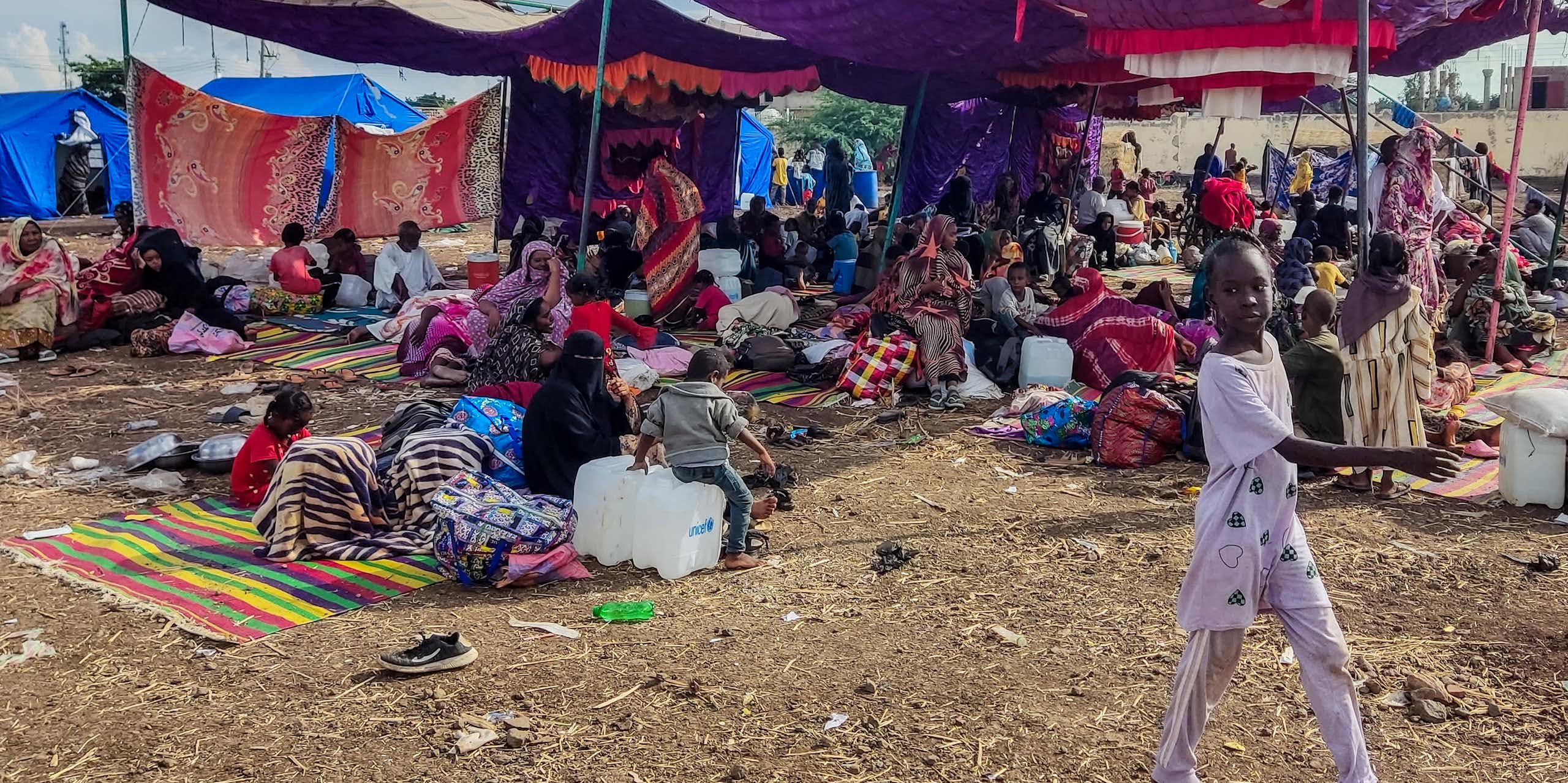 People sit and stand at a camp for the displacedin Gedaref, Sudan.