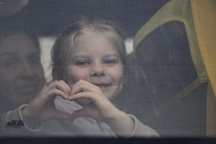 Une enfant fait un signe de cœur avec ses mains