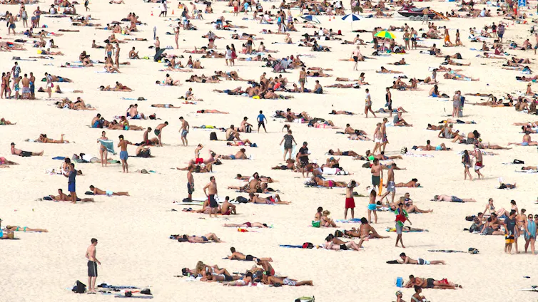 A Sydney beach scene shows many people on a beach.