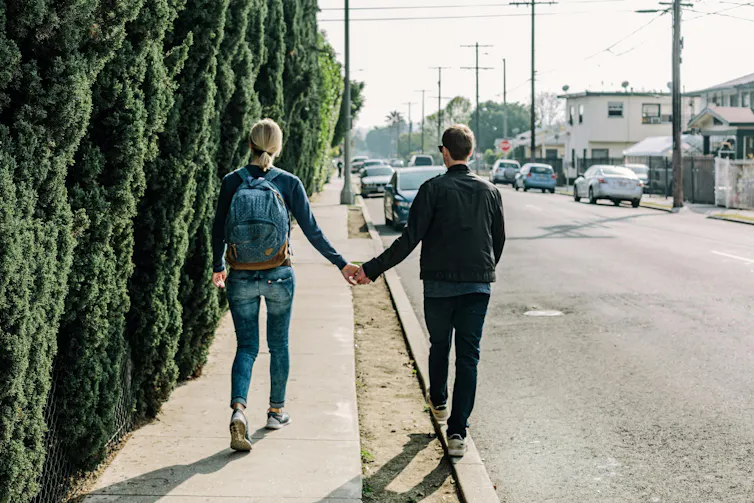 A couple walk along holding hands.