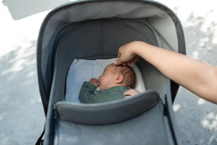 A parent adjusts the pram while their baby sleeps.