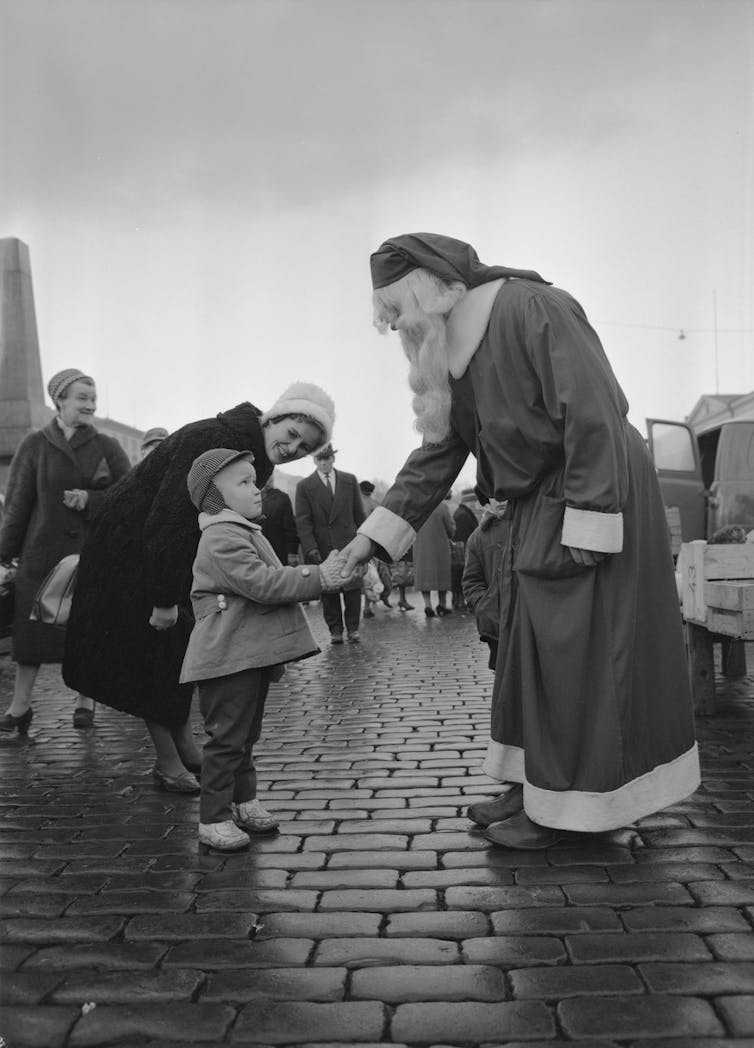 Santa shakes a boy's hand.