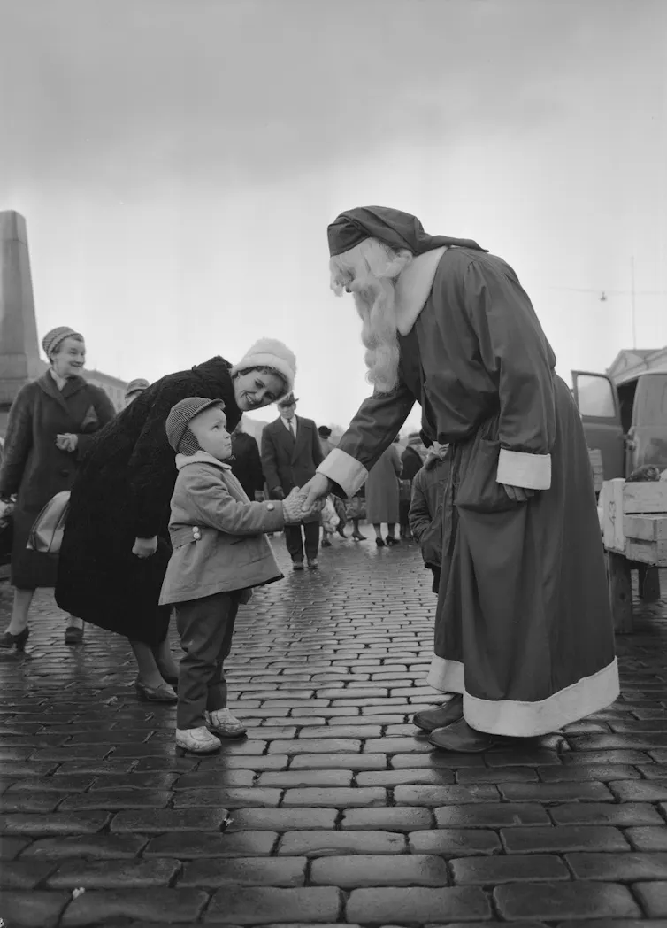 Santa shakes a boy's hand.