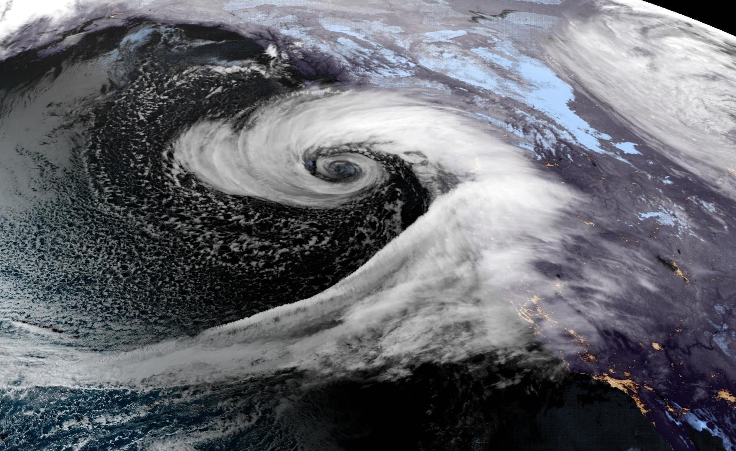 A swirl forms off the coast with a long tail of water vapor pouring into it in this satellite image.