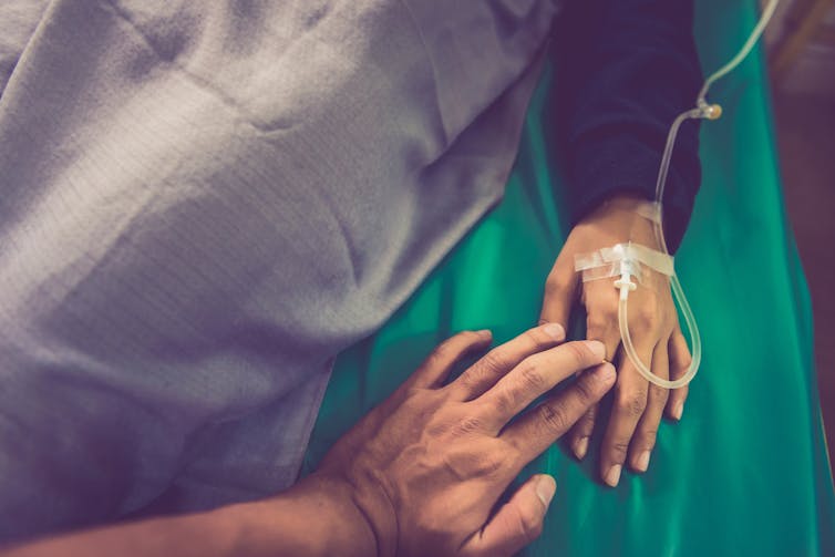 Someone is touching a person's hand in a hospital.
