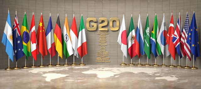 Row of flags of members of G20 Group of Twenty and list of countries in a conference room
