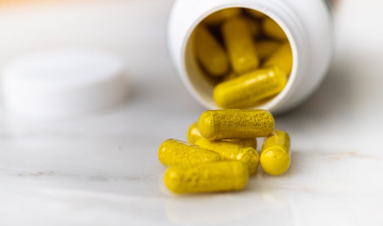 A bottle of berberine supplements spilled on its side; the yellow pills pour onto the table.