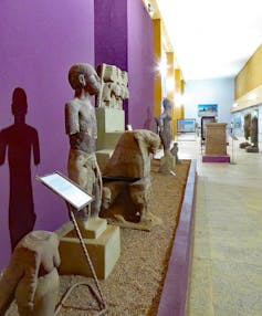 A museum interior showing a row of ancient figurines of humans, lions and other artefacts.