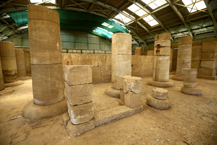 Pillars and structures with old paintings on parts of a wall housed in a structure with skylights.