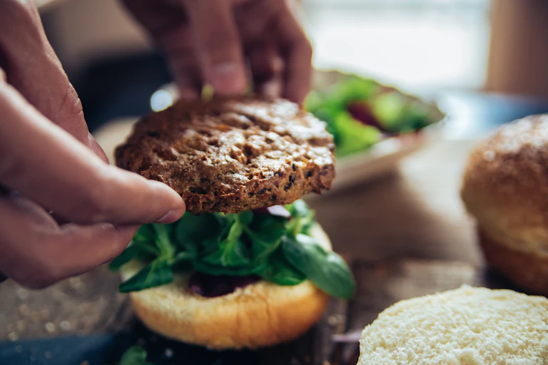 person laying a veggie burger on a bun