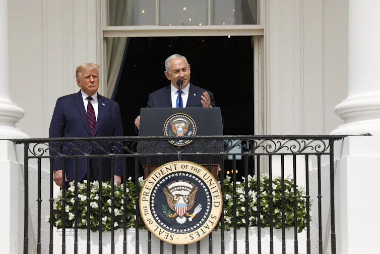 Benjamin Netanyahu speaks from a balcony at the White House while Donald Trump look on.