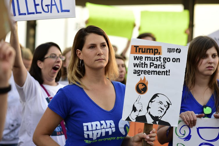 Woman holds 'Trump we must go on with Paris agreement' sign