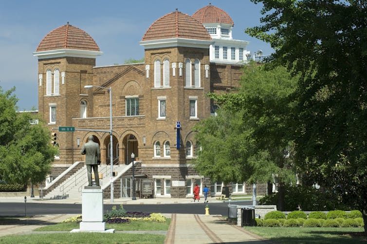 A large brown building is seen on a blue sky day.
