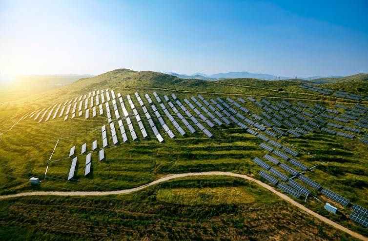 solar panels on green ridged hills, blue sky
