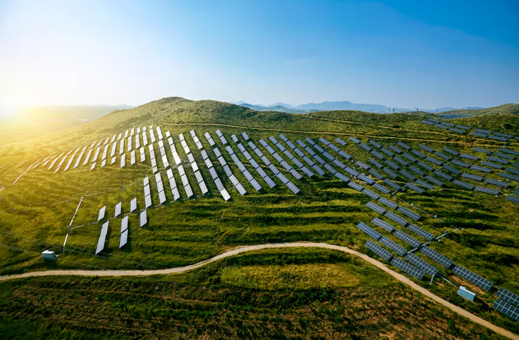 solar panels on green ridged hills, blue sky