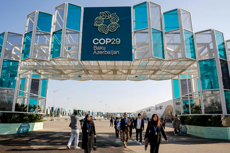 Participants walk under archway at Cop29 stadium in Baku
