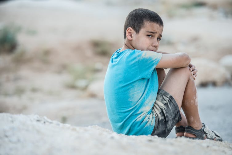 Un jeune garçon assis au sol pleure