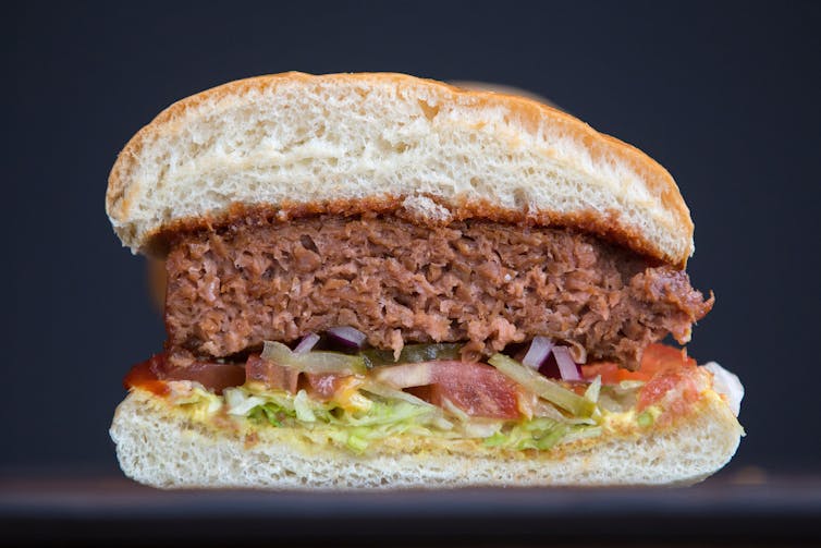 A cross-section of a plant-based burger, which is brown and looks meatlike.
