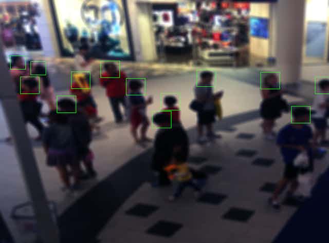 monitor view displaying people in a shopping mall with squares outlining their faces