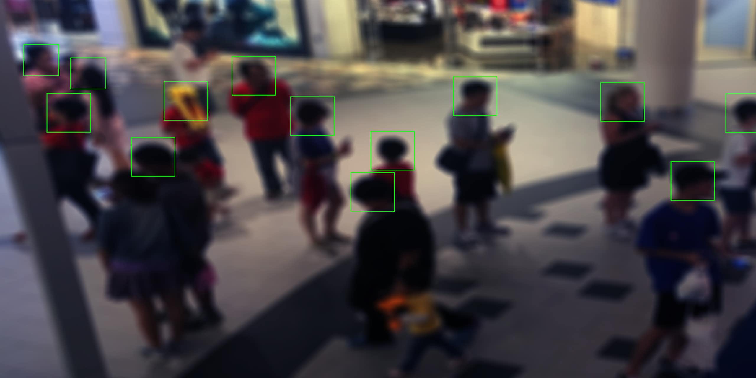 monitor view displaying people in a shopping mall with squares outlining their faces