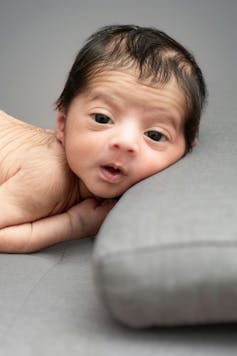 A baby is seen with a lot of hair on their back.