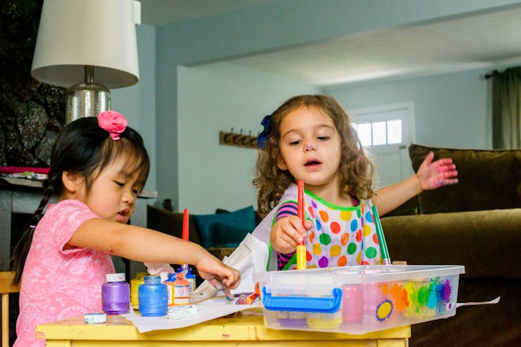 Two kids from diverse backgrounds play at a playdate.