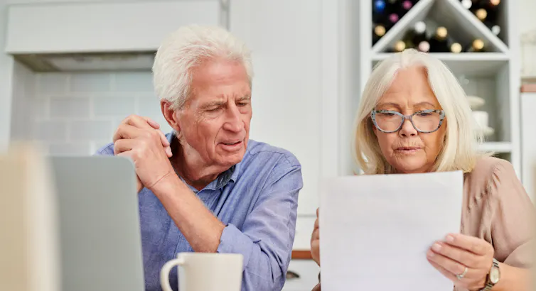 Un couple de seniors visiblement préoccupé examine des documents.