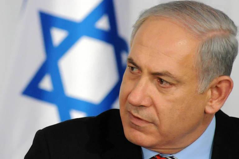 Benjamin Netanyahu with an Israeli flag behind him.
