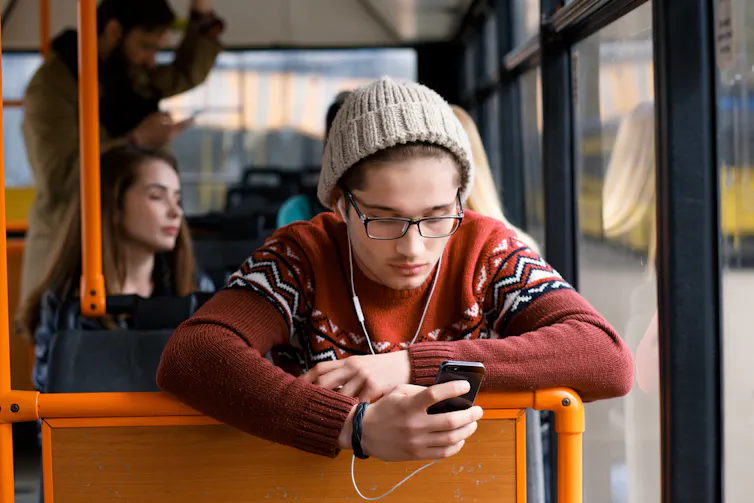 Un étudiant regarde son smartphone dans les transports