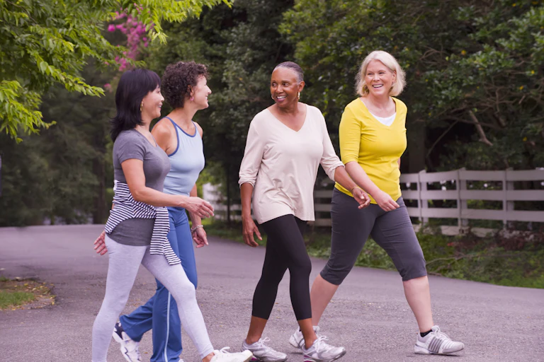 Four women in workout clothes take a walk in the park.
